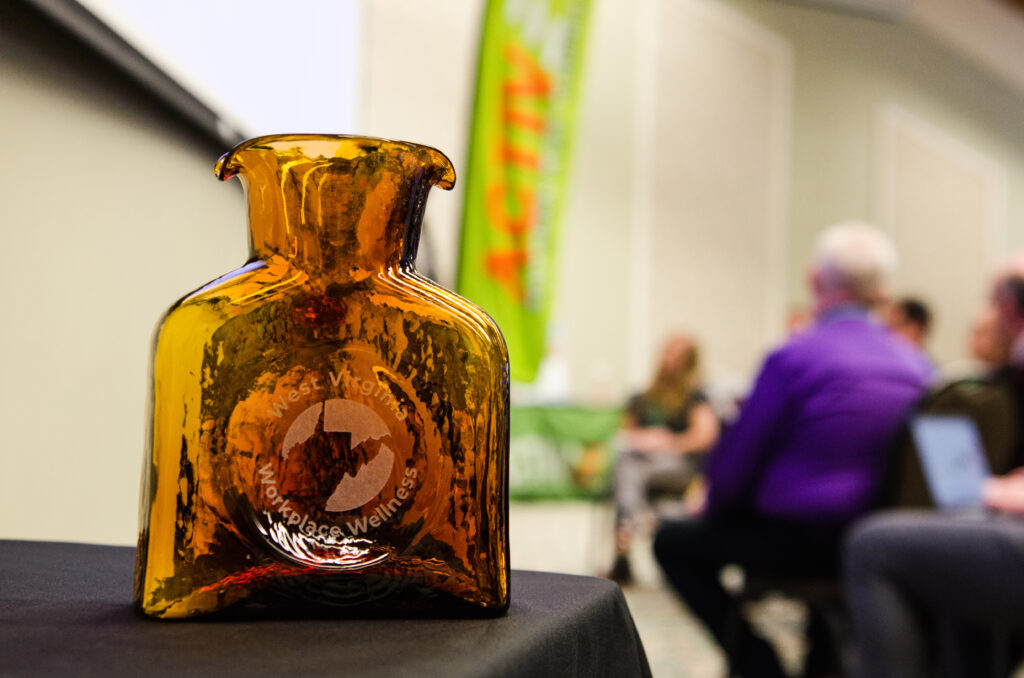 Brown Blenko glass award sitting in foreground with blurry meeting in the background